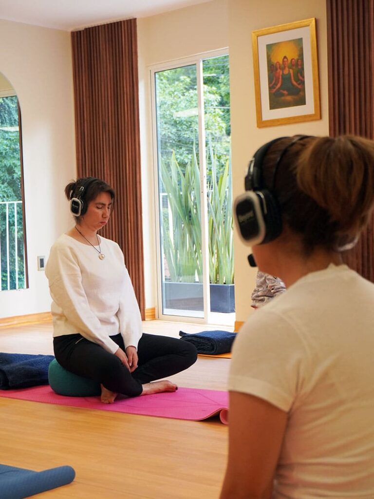 Clase de meditación guiada con alumnos en postura relajada y atención plena en Beyond Healing Center