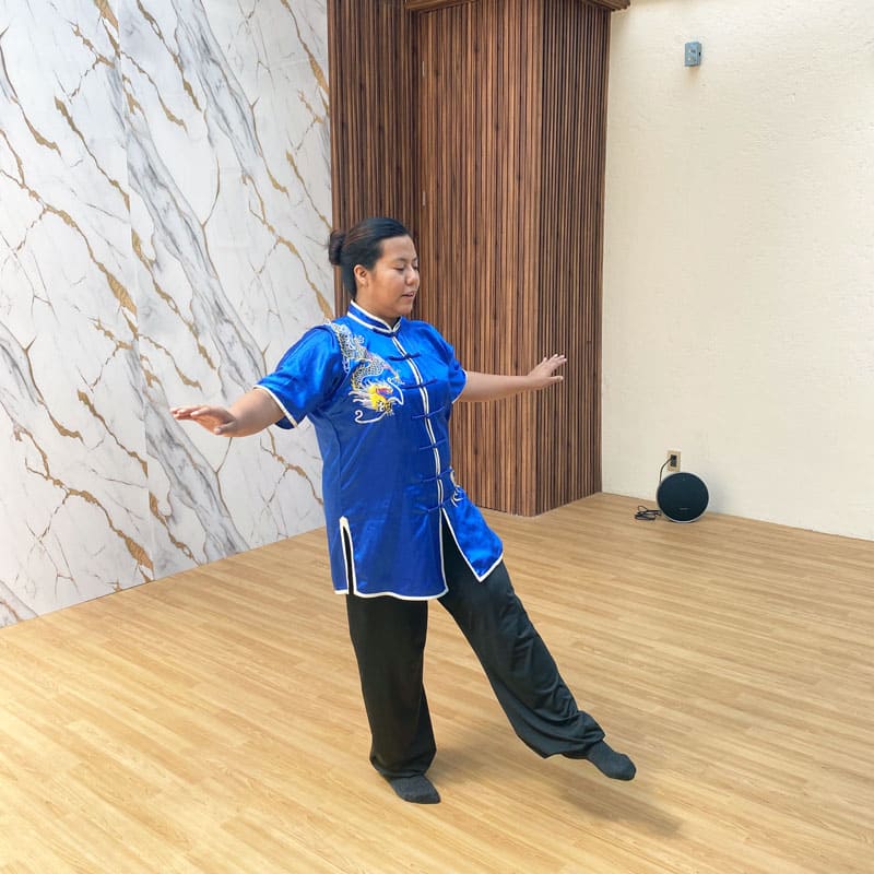 Instructor guiando una sesión grupal de Tai Chi para mejorar movilidad y relajación.